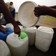 Residents fill up a containers with water from a polluted river.